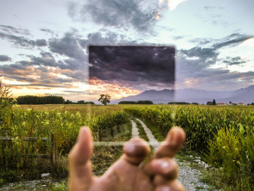 Hand holding up clear square over nature scene