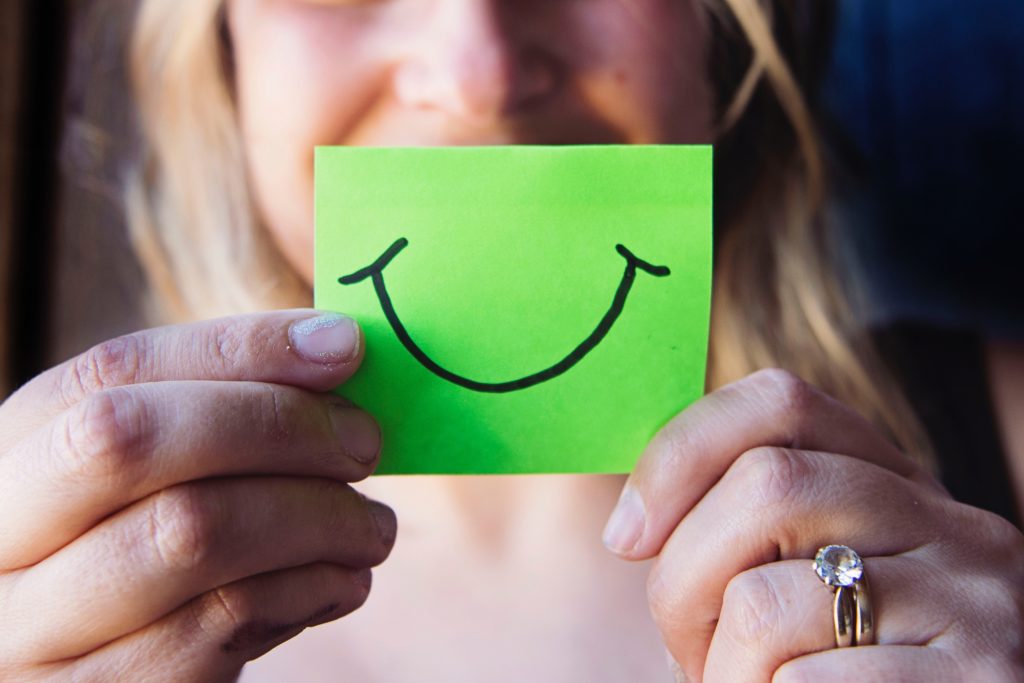 woman holding green paper with smiley face